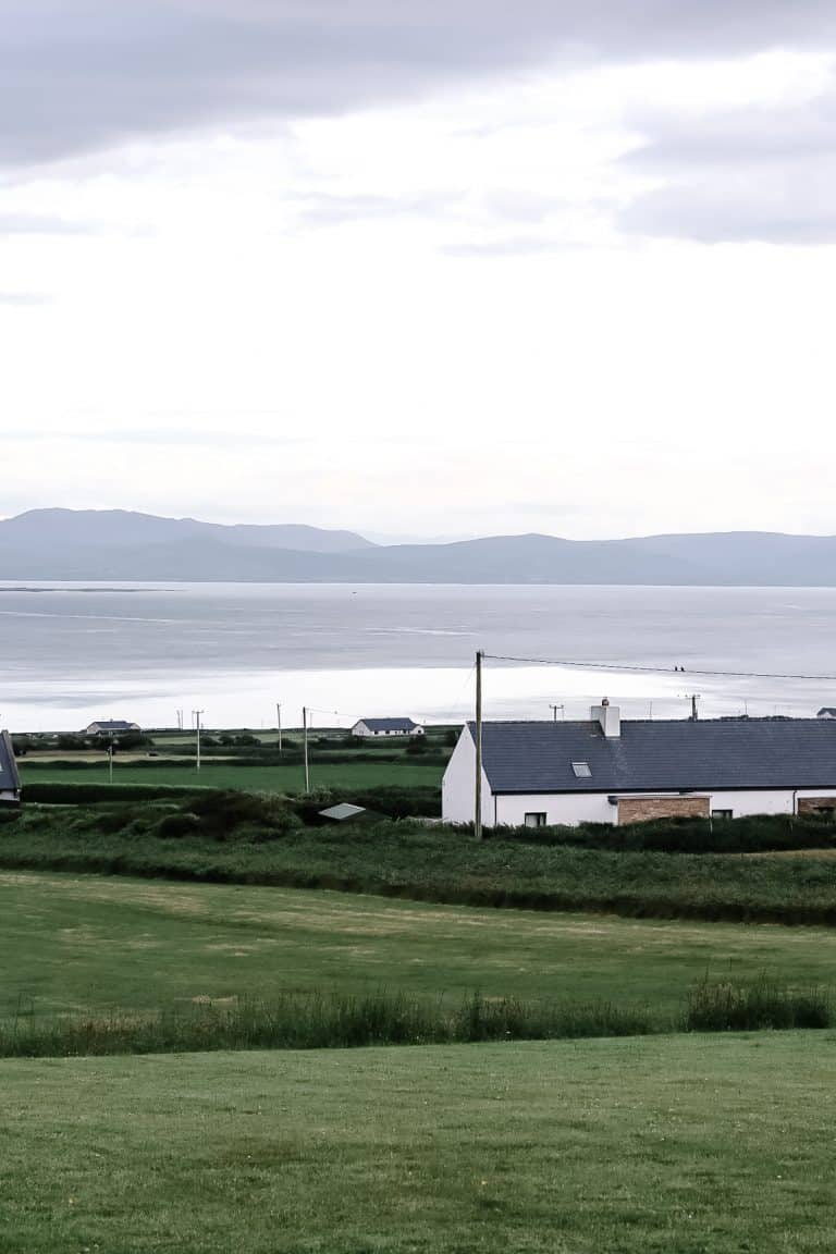 a landscape of the rollong green hills, white cottages and ballyheigue bay in co. kerry, Ireland.