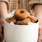 spiced apple cider doughnuts piled high in a cake tin