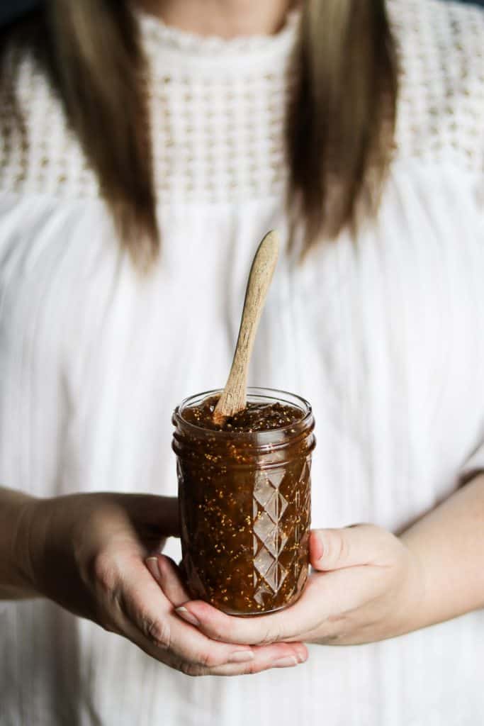 Woman holding a jar of balsamic fig jam with both hands
