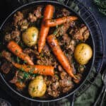 A black cast iron pot of slow cooked, Irish lamb Stew on a bench