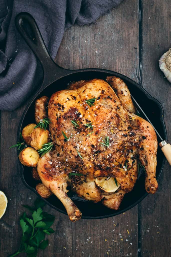 flaylay of a greek roast chicken with potatoes in a cast iron frypan