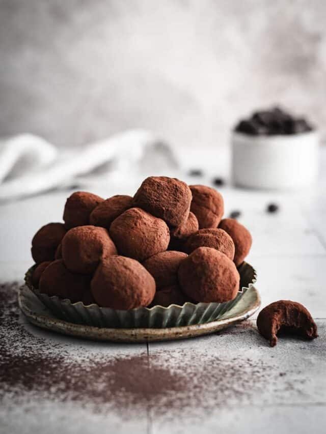 A tart tin full of homemade Bailey's Truffles. A single truffle is off to one side with a bite eaten from it.