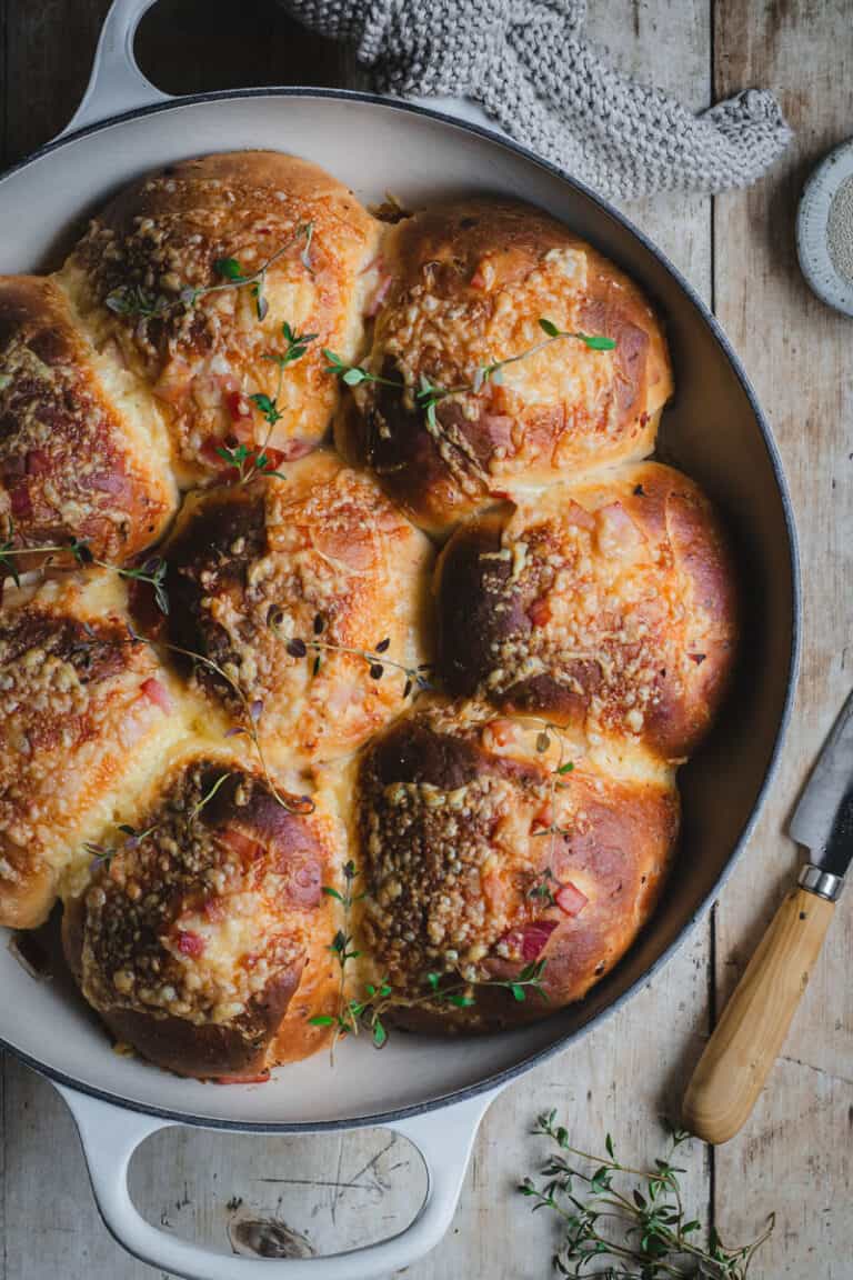 A white cast iron pan with bacon and cheese rolls baked in it.